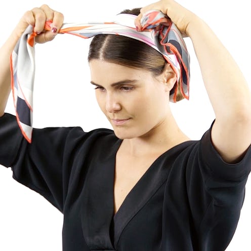 A woman styling a scarf as a headband
