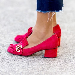 A closeup of a woman's feet in pink Gucci shoes with a thick heel 