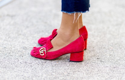 A closeup of a woman's feet in pink Gucci shoes with a thick heel 