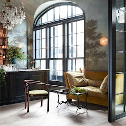 The inside of the most coveted restaurant in NYC with large windows and a mustard sofa