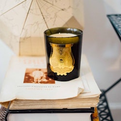 La Marquise by Cire Trudon black and gold candle resting on an old book