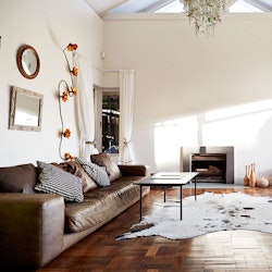 A living room with a brown leather couch, black coffee table, small fireplace, and an animal print r...