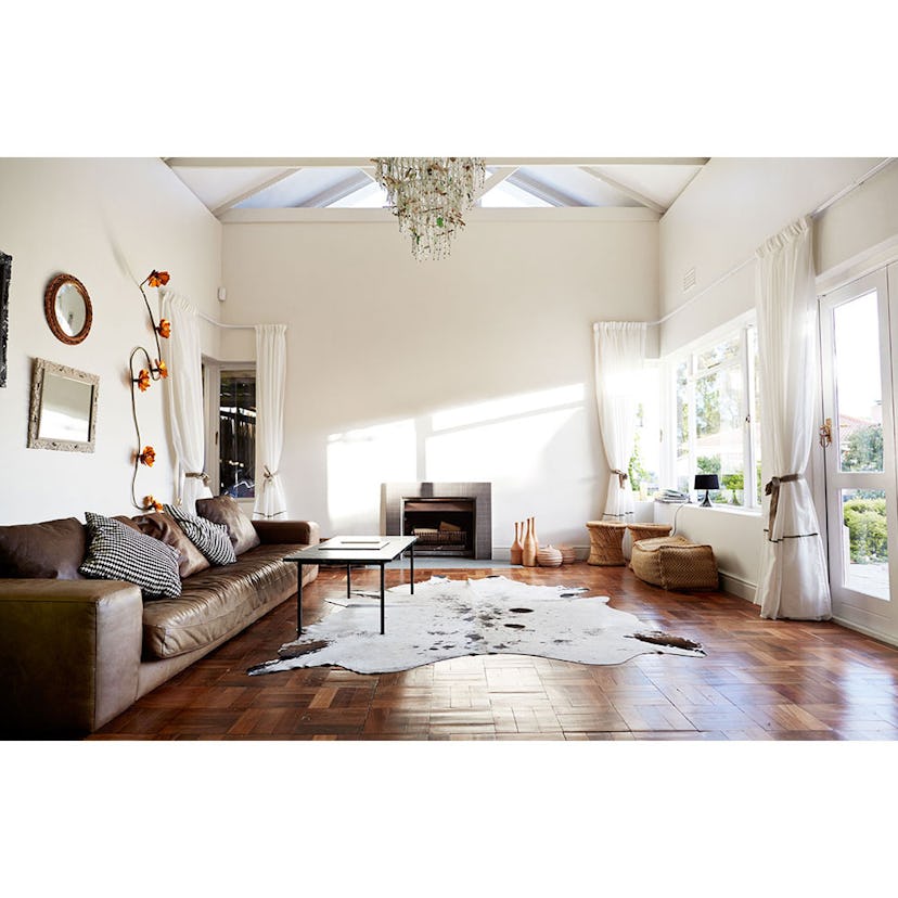 A living room with a brown leather couch, black table, small fireplace, and an animal print rug