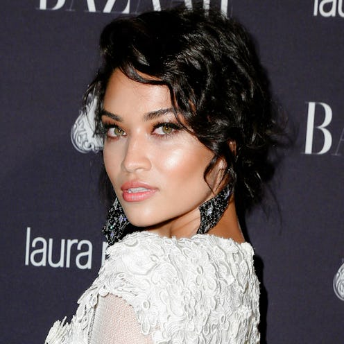 Supermodel Shanina Shaik in a white lace dress and black earrings looking over her shoulder