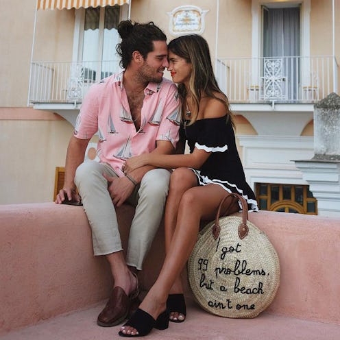 A man in a pink shirt and beige pants and a woman in a black-white dress sitting close to each other...