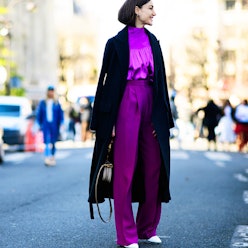 A woman standing on a street in purple work pants