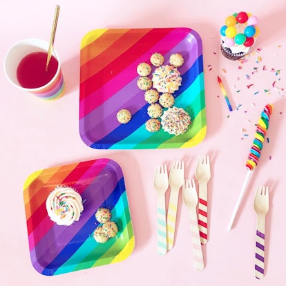 Rainbow-colored eating utensil set for kids with colorful sweets next to it