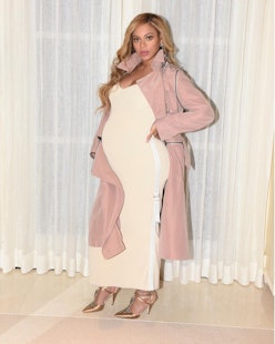 Beyoncé pregnant wearing a long white dress, a pink coat and heels