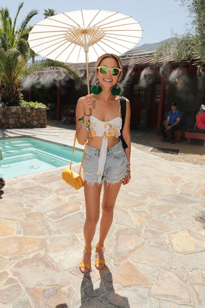 Jamie Chung posing in a white top and denim shorts 