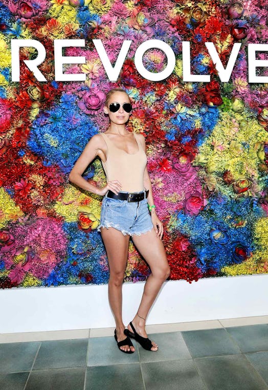 Nicole Richie posing in a light brown top and denim shorts at the Coachella