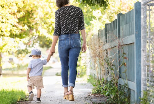 A woman walking while holding her son's hand