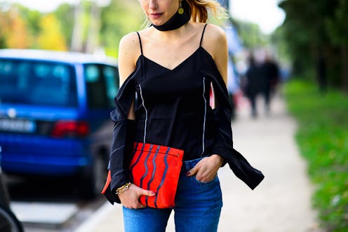 A woman in a black top and a summer novelty bag walking down the street
