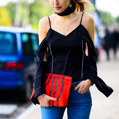 A woman in a black top and a summer novelty bag walking down the street