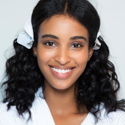 A young woman smiling with makeup on her face