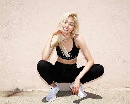 A model crouching and smiling in black non-see-through leggings and a matching top