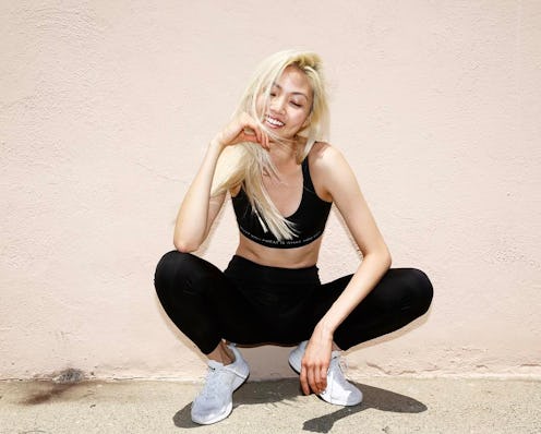 A model crouching and smiling in black non-see-through leggings and a matching top 