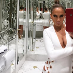 Jennifer Lopez with a high bun wearing a white lace up dress