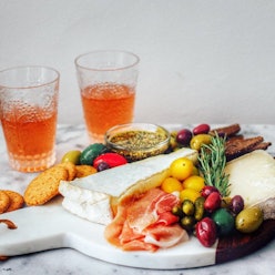 A charcuterie board full of Artisanal Snacks including various cheeses, olives, crackers and fruit