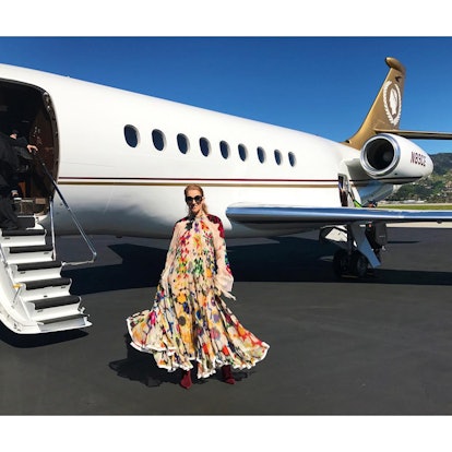 Celine Dion posing in a colorful gown in front of an airplane