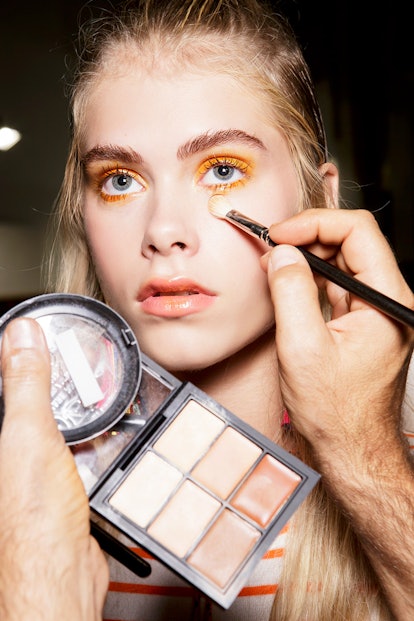 A blonde girl putting her make up on by using makeup brush sets