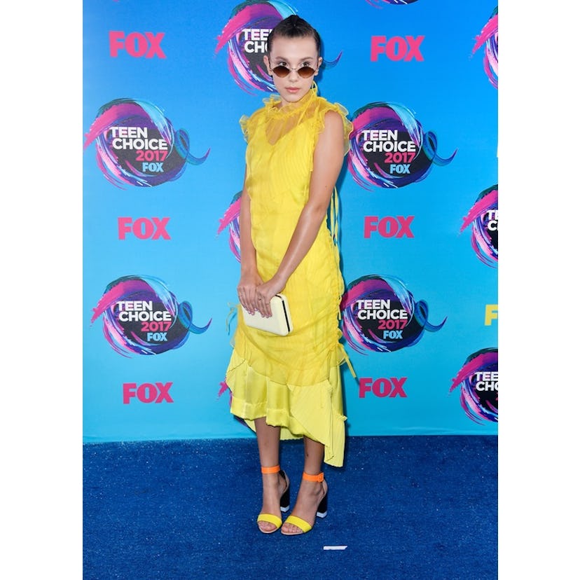 Millie Bobby Brown posing in a yellow dress at The 2017 Teen Choice Awards