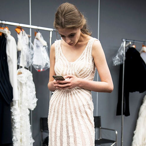 A bride in a wedding dress typing on her smartphone