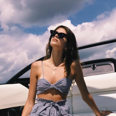 Kaia Gerber celebrating the end of summer on a yacht in a grey bikini top, matching shorts and sungl...
