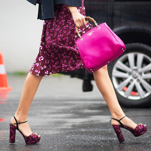A woman walking in a heart-patterned knee-length skirt and matching heels, accessorized with a pink ...