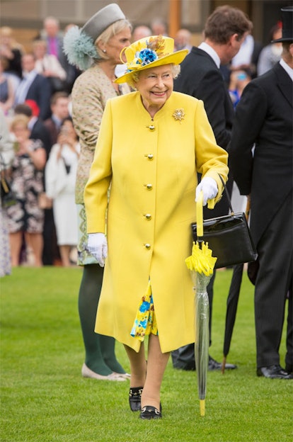 The Queen walking in a bright yellow coat and a hat matching her dress.