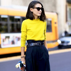 A woman wearing a yellow sweater and a black skirt as some of the under-$100 statement pieces only f...