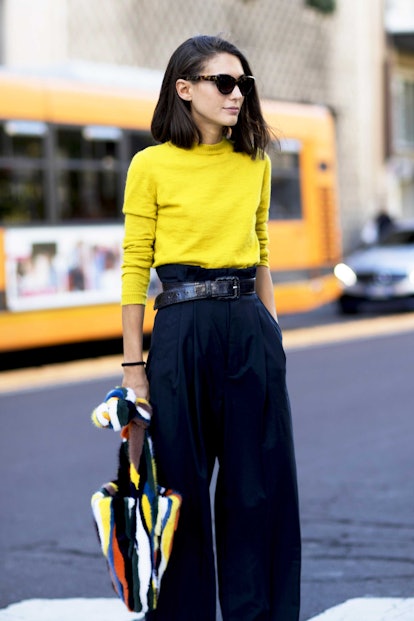 A woman posing in a yellow sweater and black skirt 