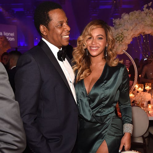 Beyoncé in a dark green dress and Jay Z in a tuxedo, smiling for a photo
