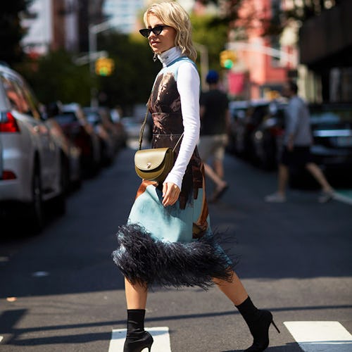 A model crossing the street in a dress and shirt underneath, with affordable black ankle boots 