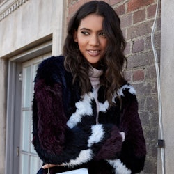 A model in a black and white faux fur coat with a white Rachel Zoe box clutch