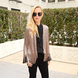 Rachel Zoe in a shimmery fringed cardigan over an all-black ensemble of a dress shirt and flared pan...