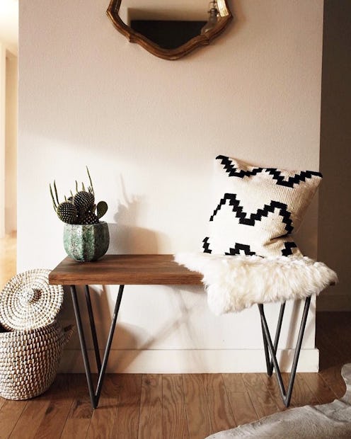 A wooden table with a potted cactus and two throw pillows