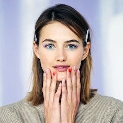 A female model posing with many beauty products on her face