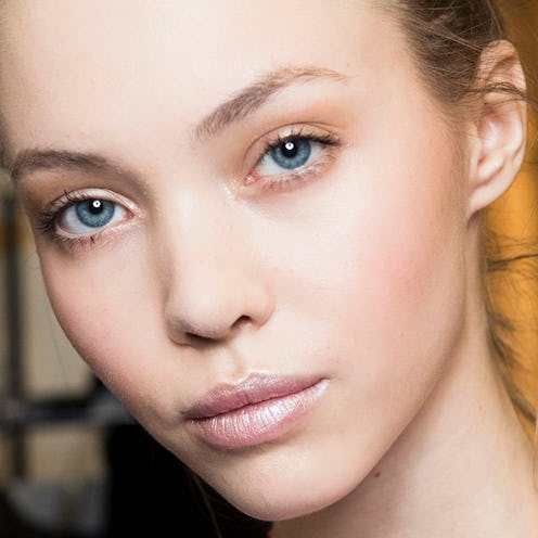 A close-up of a blonde woman with blue eyes and flawless skin