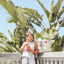 Remi Ishizuka poses with banana leaves in background, holding her nutrient-rich summer smoothie.