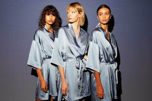 Three women in blue silk capes posing with clear skin without acne issues