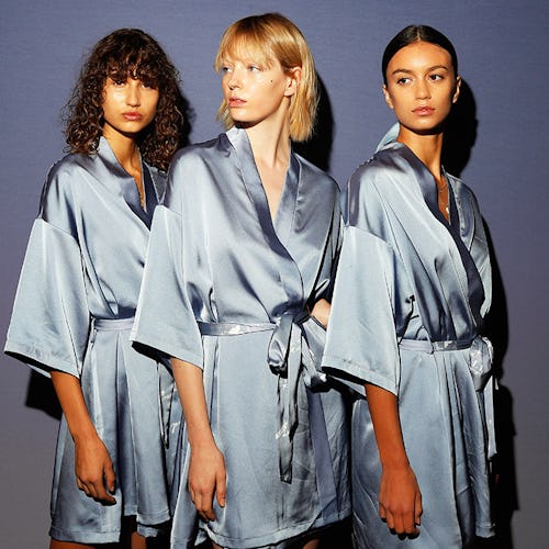 Three women in blue silk capes posing with clear skin without acne issues