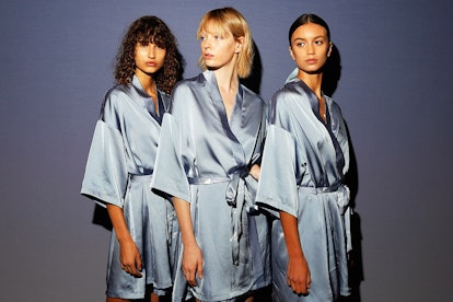 Three women in blue silk capes posing for a photo