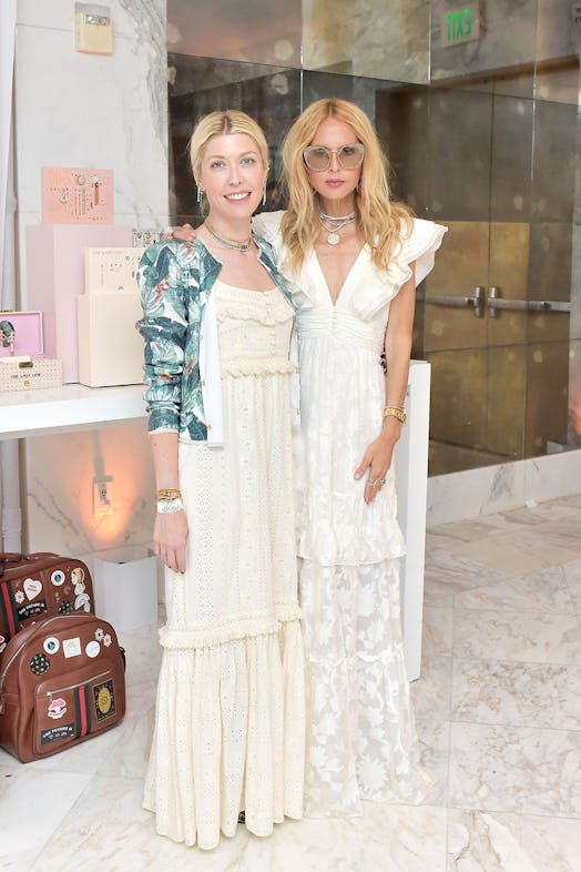 Two blonde women in full white outfits posing for a photo