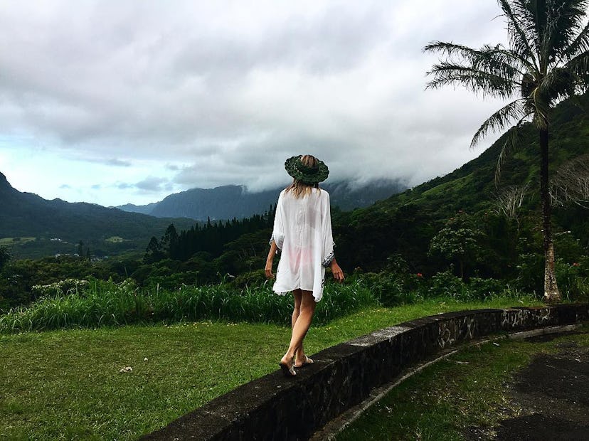 Back of a blonde girl that is walking in a white cardigan at the Hawaiian Islands