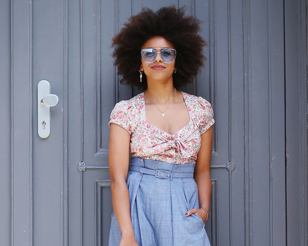 A model in high-waisted, flared blue pants and a tucked in floral top 
