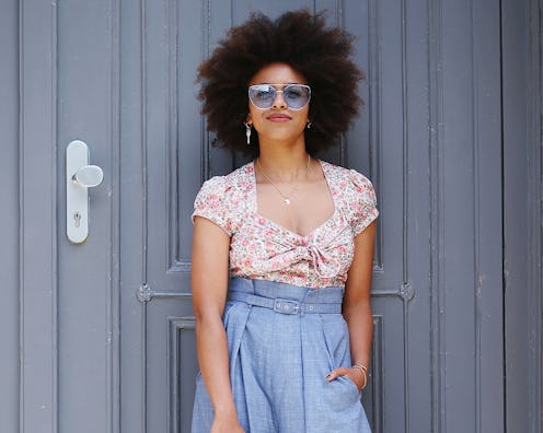 A model in high-waisted, flared blue pants and a tucked in floral top 