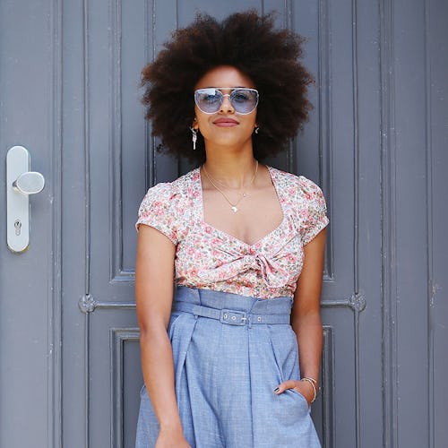 A model in high-waisted, flared blue pants and a tucked in floral top 
