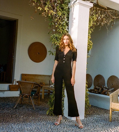 Young model posing in a black jumpsuit and sandals