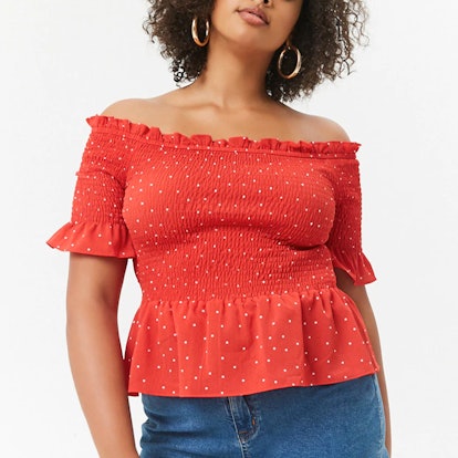 A woman posing in a red plus size polka dot top