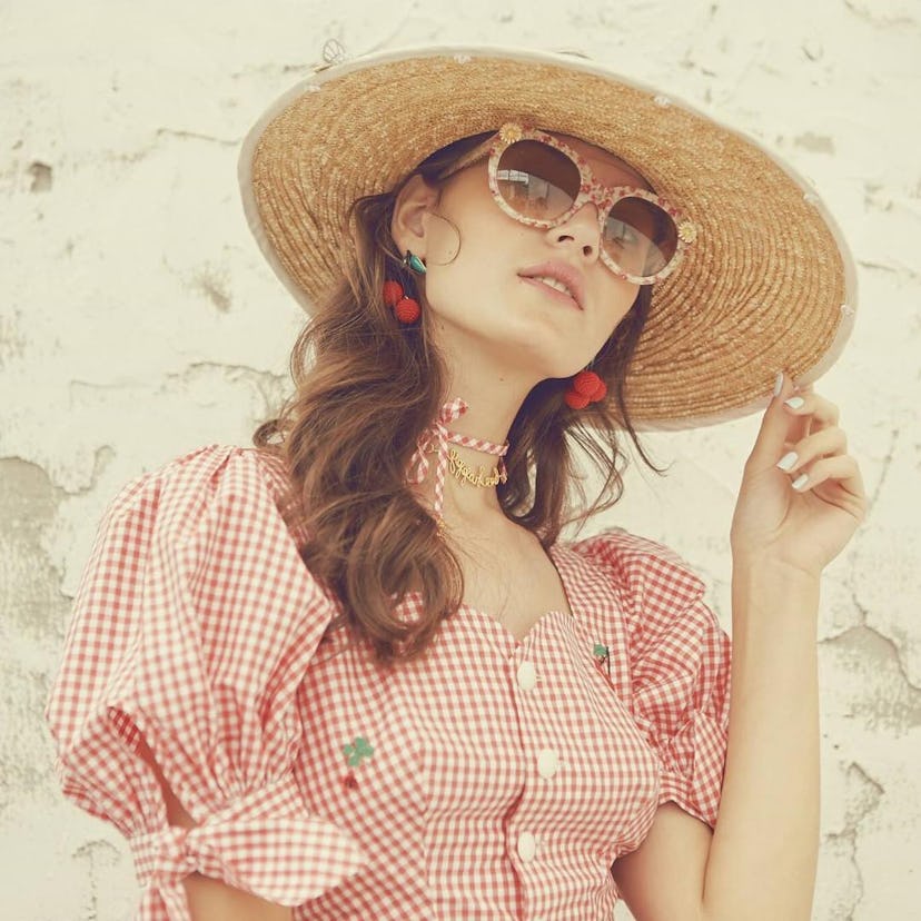 A model posing in a romantic blouse and a straw hat from the chic Asian brand, Strestis